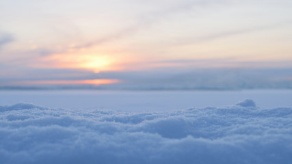 Soft winter scene. Snowbank on the foreground and blurred background with sunset and snowy river. Copy space