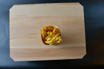 French fries on a wooden board isolated on black