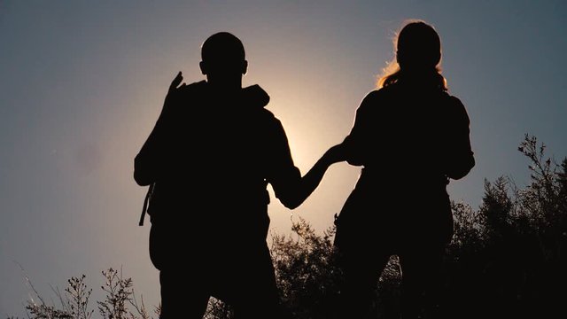teamwork tourists travel concept slow motion video. hiking silhouette happy family couple man and girl go hiking lifestyle climbing a mountain. walking on nature. tourists with backpacks traveling