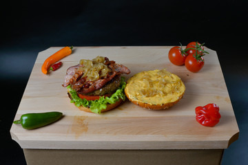 An appetizing hamburger on a wooden board with fresh vegetables.