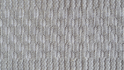 Lace stitch pattern with leaves on white backround. Neutral gray color knitted texture. Closeup