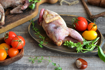 Raw fowl partridge and fresh vegetables on a table, rustic style