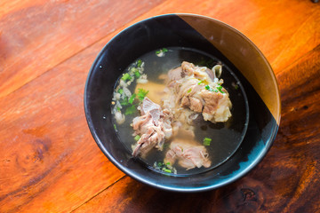Delicious pork bone soup put on a black cup on a wooden table