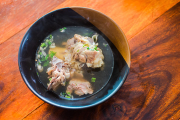 Delicious pork bone soup put on a black cup on a wooden table