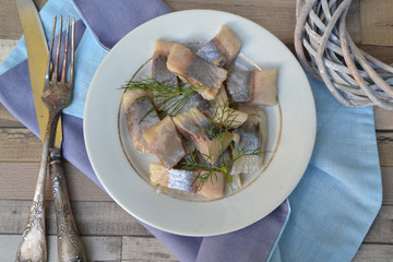 Marinated herring on plate with fresh dill on shabby table, russian food