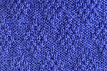 Blue wool yarn knitted texture with large stitches. Hand knitted rhombus pattern. Closeup