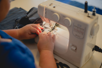 Female hands on an sewing machine sew denim. Close-up