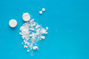 White squashed tablets pills on blue background. Copy space