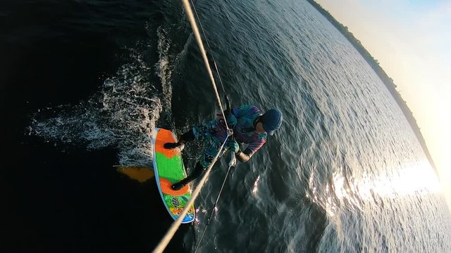 Male kitesurfer is standing up back onto the board