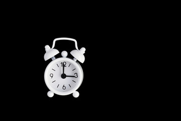 White metal alarm clock isolated on black background.Three o'clock. Copy space
