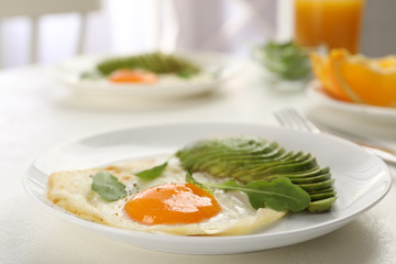 Tasty breakfast with fried egg and avocado on light table