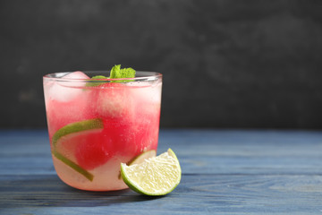 Glass of refreshing watermelon drink on blue wooden table against dark background. Space for text