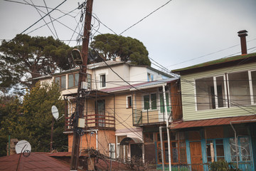 Dangerous plexus of electrical wires on a pole, against the background of residential buildings in the city.