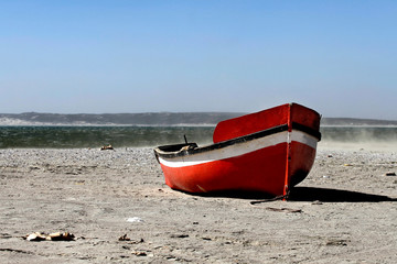 Colored, red fisher boat on village beach in sourth africa