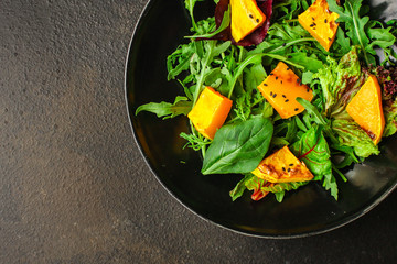 healthy salad pumpkin and mix leaves  lettuce (arugula, spinach, red chard and other ingredients) menu concept. food background. copy space. Top view