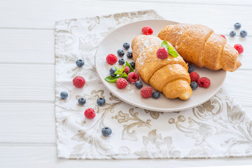  croissants on a white plate with berries breakfast in Paris for a beloved food on a date