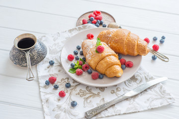  croissants on a white plate with berries breakfast in Paris for a beloved food on a date