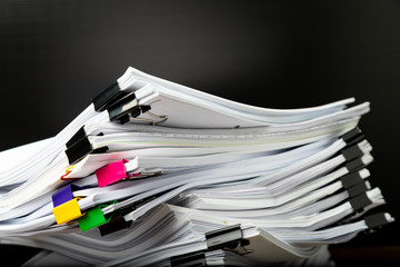 Stack of overload document paper with colorful paperclip with black background.