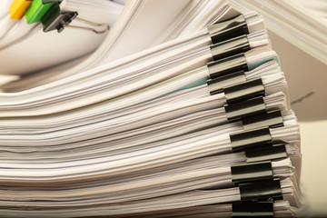 Stack of overload document paper with black paperclip.