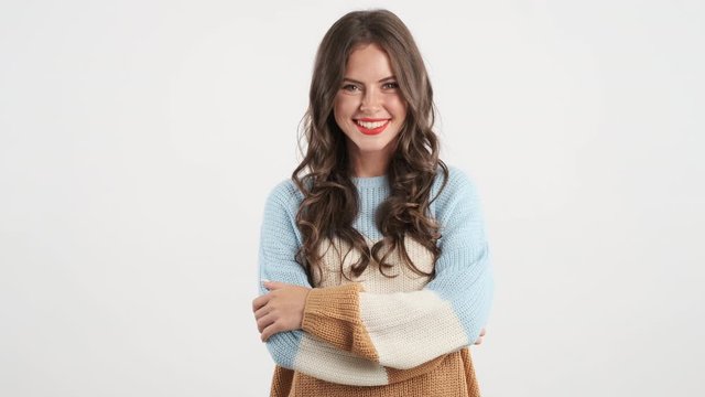 Beautiful cheerful brunette girl in cozy sweater happily looking in camera isolated