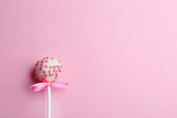 Tasty cake pop with bow on light pink background, top view. Space for text