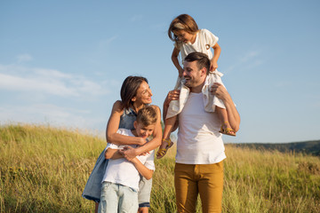 Happy family in nature. Mom and dad with the children having fun on the outing.