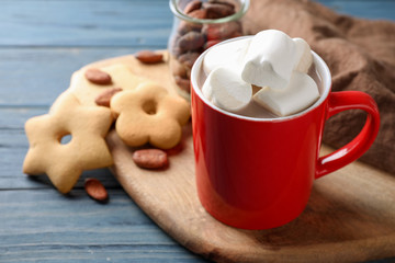 Composition of tasty cocoa with marshmallows in cup on blue wooden table. Space for text
