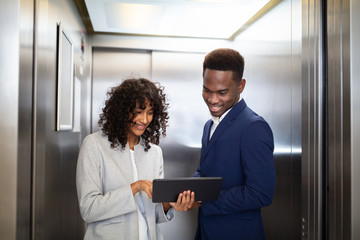 Businesspeople Discussing Standing Inside Elevator © Andrey Popov