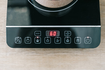 Pot at small electric stove with control panel in kitchen