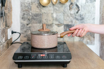 Girl cooking food in kitchen with small electric stove