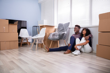 Couple Sitting On Floor Inside Their New Home