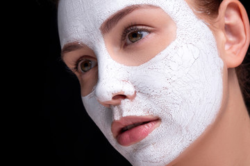 Beautiful young european woman apply clay mask on her face. beauty spa concept