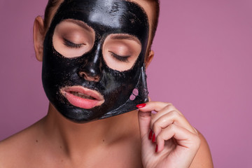 Beautiful young european woman apply clay mask on her face. beauty spa concept