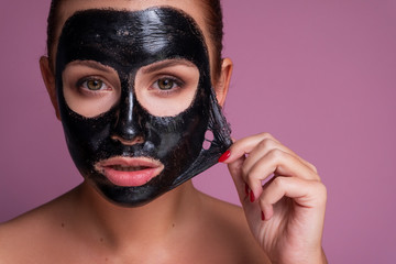 Beautiful young european woman apply clay mask on her face. beauty spa concept