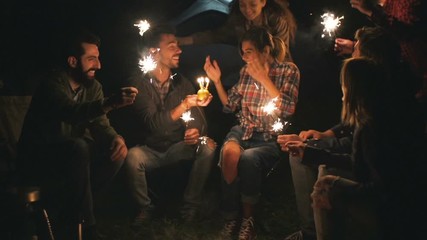 Couple celebrate their birthday with friends camping at night in the mountains