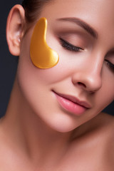 Obraz na płótnie Canvas Beautiful brunette european woman apply patches on her face undey eyes to get rid of circles, preparation before make up. Beauty spa procedure concept