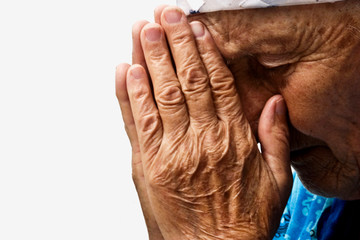 Fototapeta premium Old praying grandmother. Mother knelt in prayer for the children. Close-up of a praying woman face. Tearful prayer to God