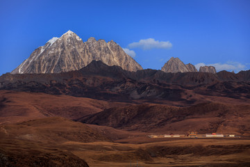 Tagong Prairie Grassland, Lhagang Grassland, Tibetan area of Sichuan Province China. Buddhist Monastery in foreground, Yala Snow Mountain towering in the distance. Strange Martian Landscape