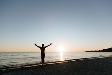 Young man looking at sunset by the sea