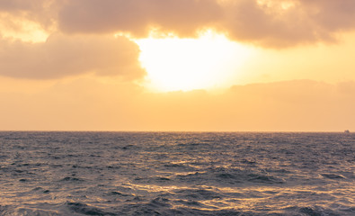 Fototapeta na wymiar dramatic evening sunset cloudy sky above wavy sea water surface, horizon nature background simple scenery landscape 