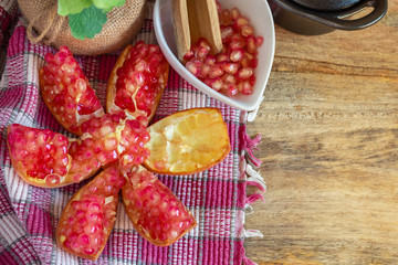 Pomegranate, red fruit open on cutting board, clay pots and rag