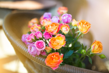 bouquet of roses in a rattan chair on the terrace of the cafe in a bright summer sunshine backlit