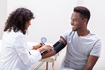 Young Doctor Checking Blood Pressure - obrazy, fototapety, plakaty