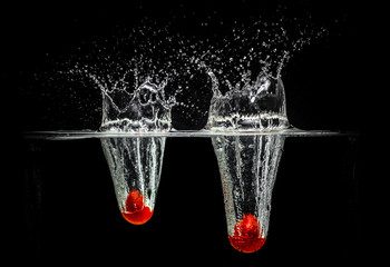 Water Splash Photography: Two tomatoes falling in water creating a large splash, on a black...
