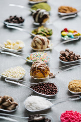 Food in spoons. Variety of  chocolate, hazelnut, peanut, pistachio, bonbon, wafer rolls, white chocolates, dark chocolates, milky chocolates, bite dessert, granulated sugar, crunch, coconut powder