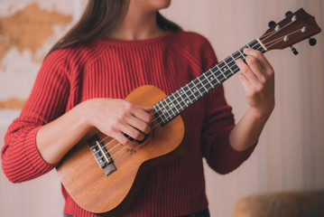 Young girl playing ukulele or guitar. Four string instrument, acoustic. 
