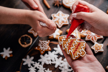 Christmas, New Year, DIY, holidays preparation and creativity concept. Getting ready to celebration. Friends decorating homemade gingerbread cookies with icing - Powered by Adobe