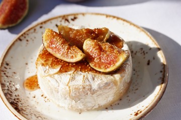 Baked Camembert cheese with fig jam and fresh figs, hard sunlight, deep shadow. sunny weather. fashion light, copy space