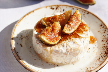 Baked Camembert cheese with fig jam and fresh figs, hard sunlight, deep shadow. sunny weather. fashion light, copy space