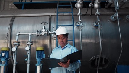 An asian senior engineer or mechanic reading manual in front of fuel power tank